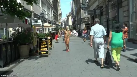 Blonde nue marche dans les rues animées
