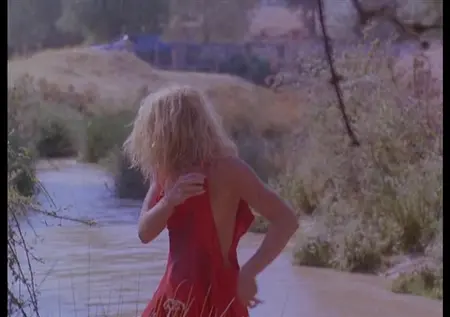 La blonde nue efface la robe dans la rivière