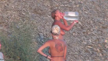 Les filles nues se lavent sous une douche sur une plage publique