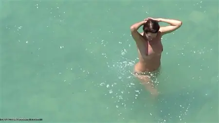 Le gars s'enlise derrière les paires nues qui se baignent dans la mer