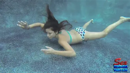 Une fille mince essaie de sucer une bite en caoutchouc sous l'eau