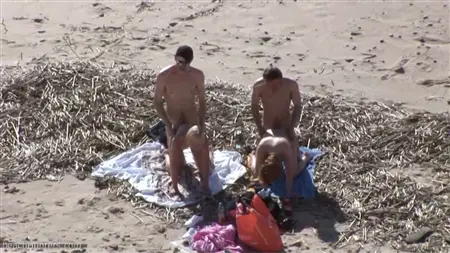 Une foule de gars sur la plage laisse un cercle de deux prostituées